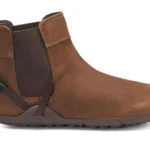 A brown ankle-high leather Chelsea Boot from Xero Shoes with a pull tab at the back, elastic side panel, and dark rubber sole. This stylish design also features a small strap detail near the heel for modern flair.